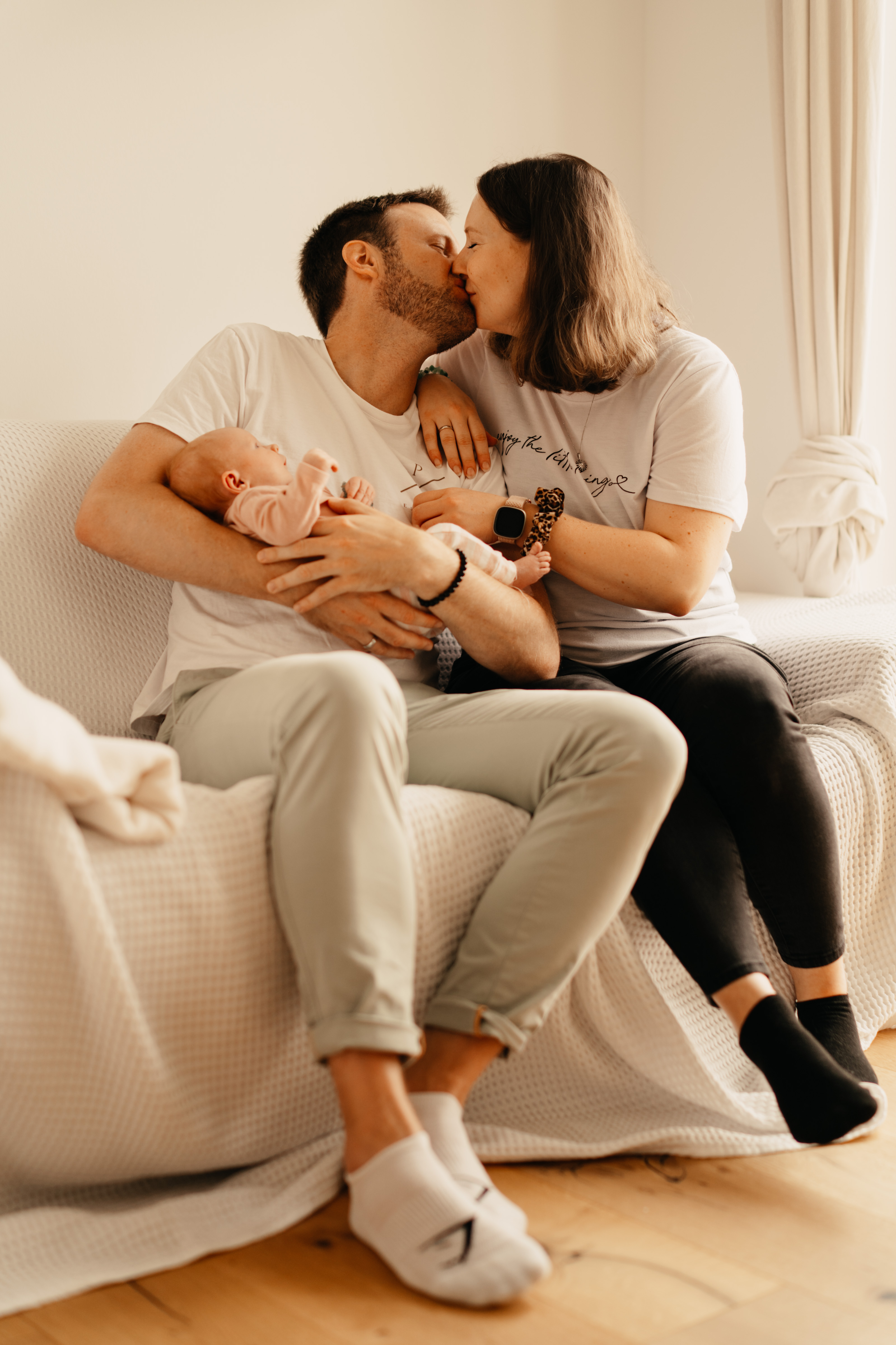 Großes Geschwisterkind hält das neugeborene Baby vorsichtig im Arm