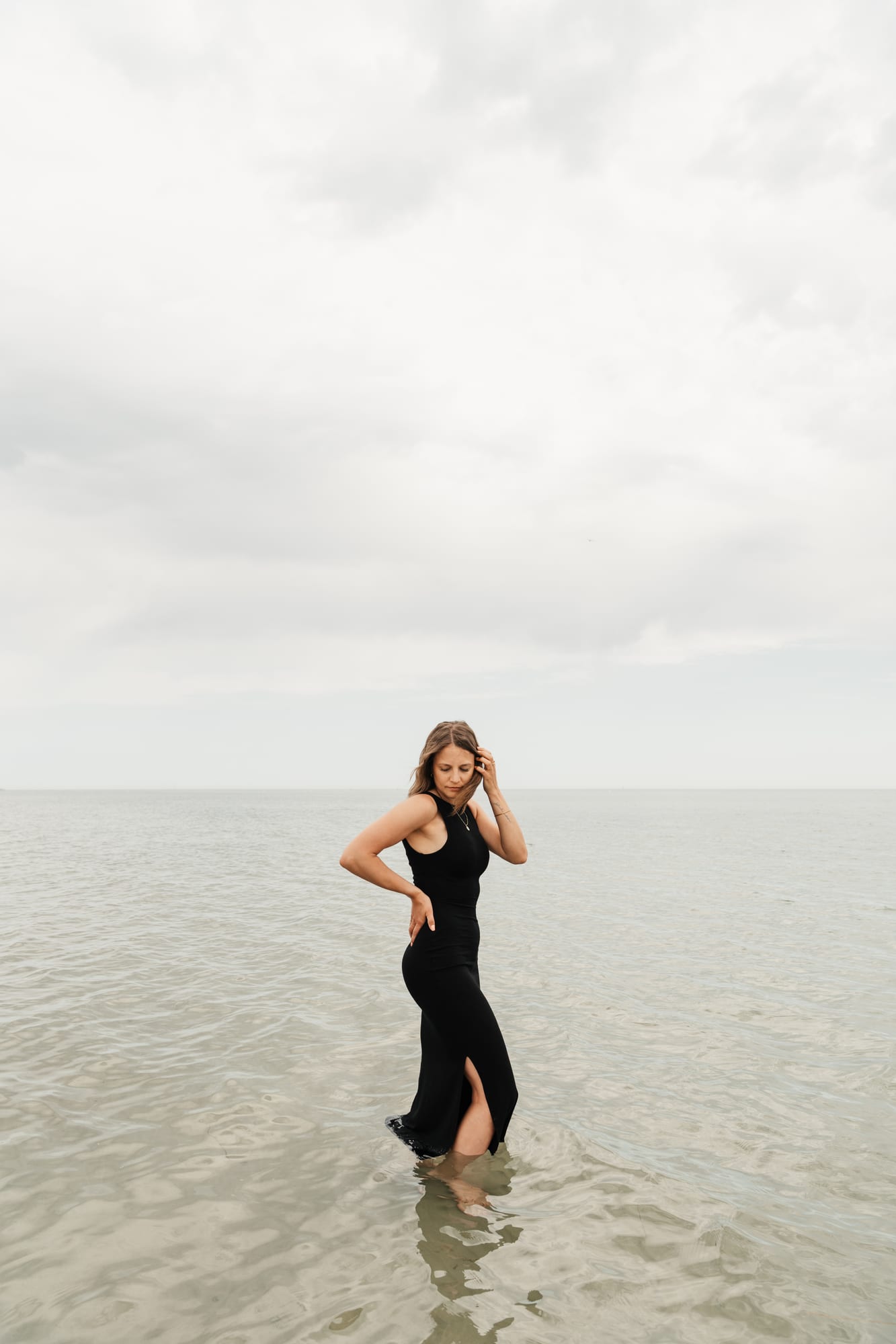 Lena steht im schwarzen Kleid im ruhigen Wasser der Ostsee