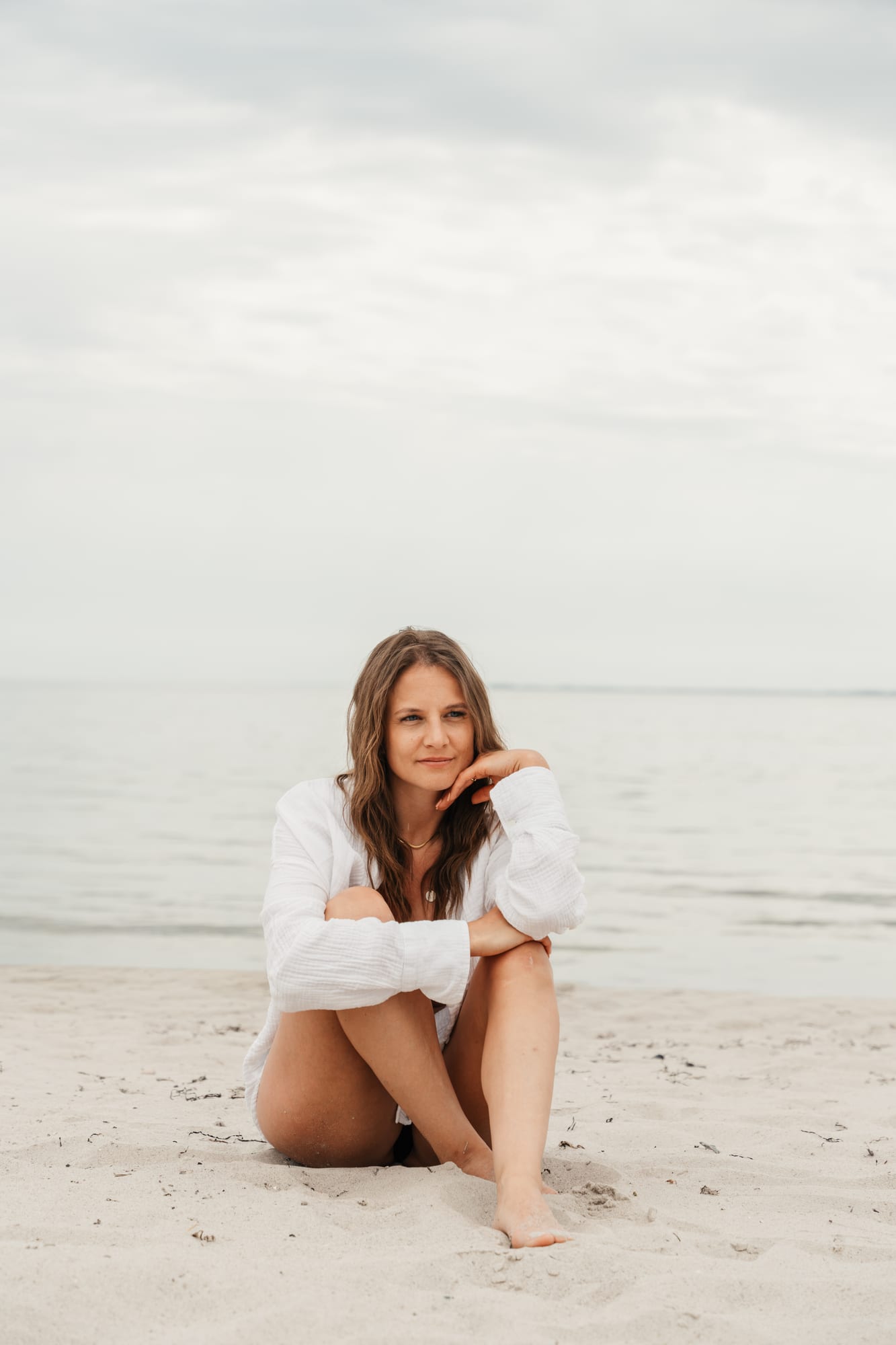 Lena sitzt am Strand, den Kopf in die Hand gestützt