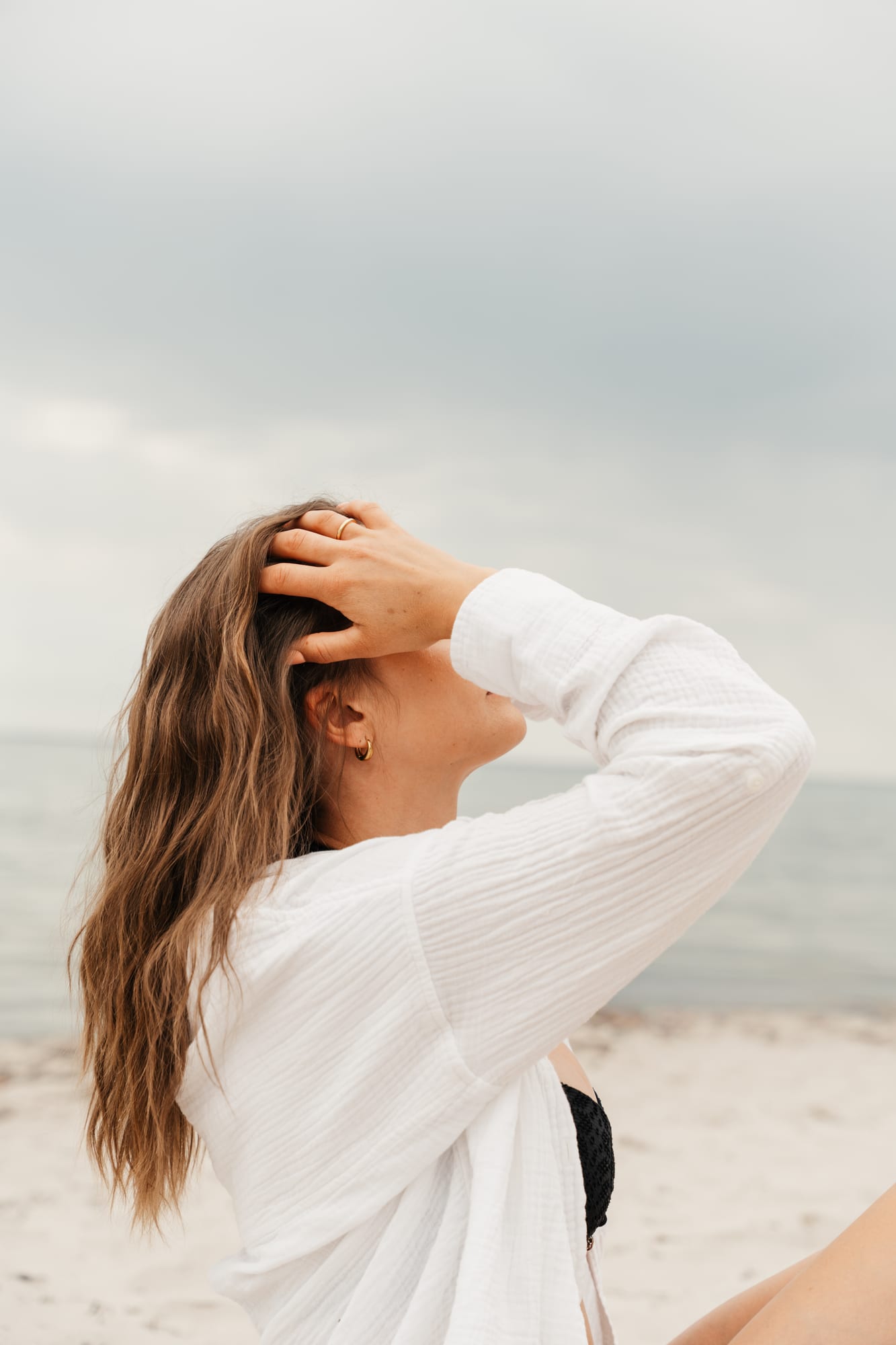 Lena fährt sich mit der Hand durchs Haar, weiche Strandstimmung