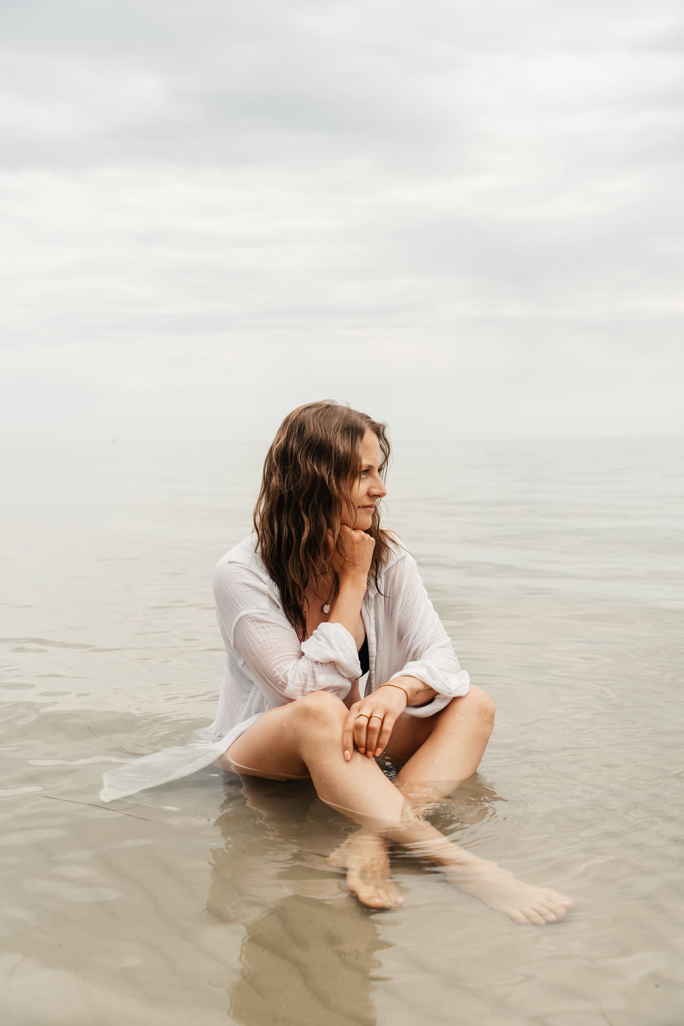 Lena sitzt am Wassersaum der Ostsee