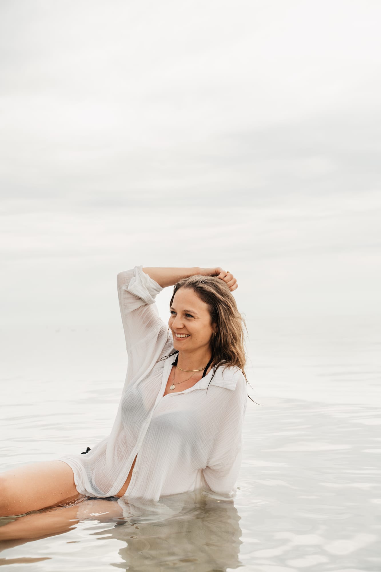 Lena im flachen Wasser, die Hände im Haar
